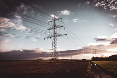 Low angle view of electricity pylon on field against sky