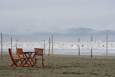 Chairs on beach against sky