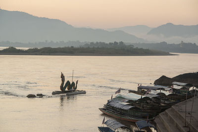 People in boat on sea against mountains