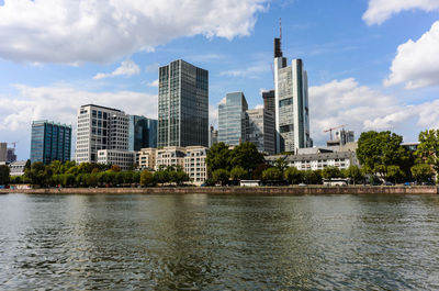 River by modern buildings against sky in city