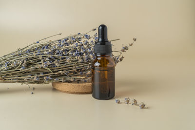 A face serum or oil in a brown dropper bottle standing on a beige table background 