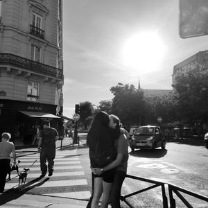 People walking on city street against sky