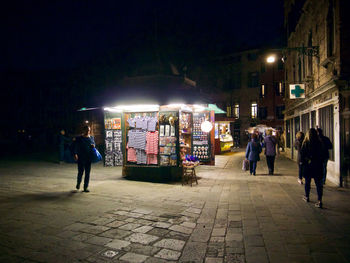 People walking on illuminated street at night