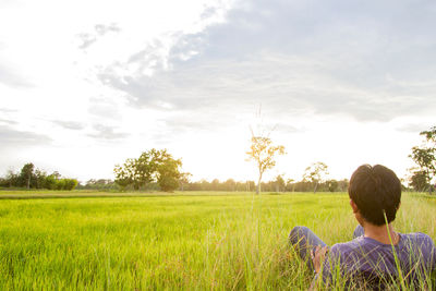 Rear view of man on field against sky