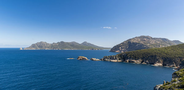 Scenic view of sea and mountains against clear blue sky