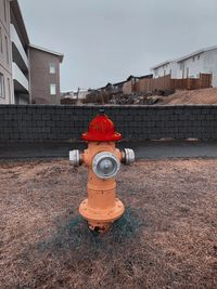 Fire hydrant on field by building against sky