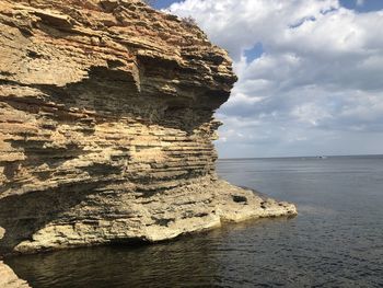 Rock formation in sea against sky