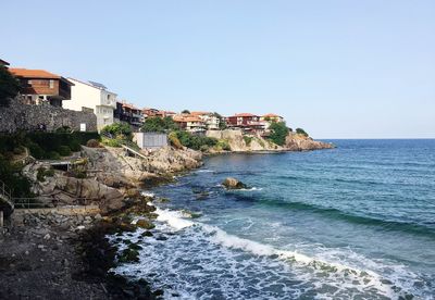 Buildings by sea against clear sky