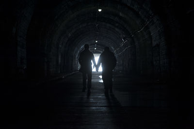 Rear view of silhouette people walking in tunnel