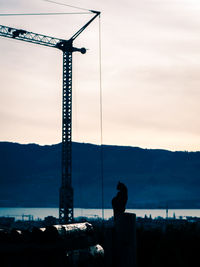 Silhouette of crane against sky during sunset