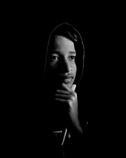 Portrait of young boy against black background