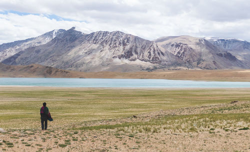 Rear view of man standing on field against sky