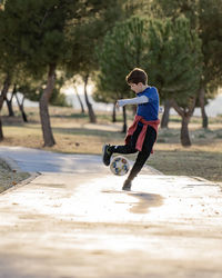 Little boy juggling soccer ball in nature. child kicking ball. football player on practicing