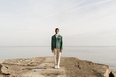 Young man standing on damaged pier against sky