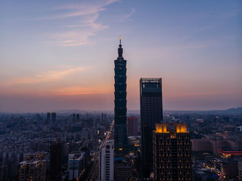 Modern buildings in city against romantic sky at sunset