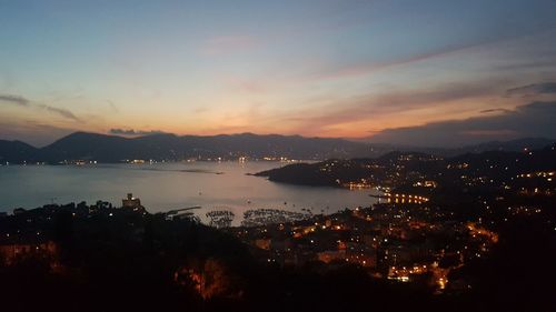 Illuminated cityscape against sky at sunset