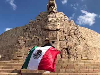 Woman holding mexican flag against historic building