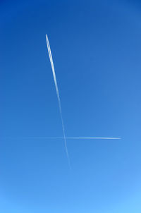Intersecting vapor trails in a clear blue sky