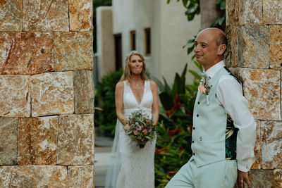 Wedding couple  standing against wall