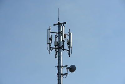 Low angle view of telephone pole against clear blue sky