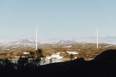 Windmills on mountain against clear sky