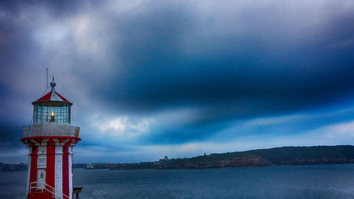 Lighthouse amidst sea and buildings against sky