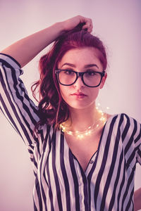 Young woman with illuminated string light against gray background