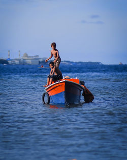 Portrait of kids kayaking in sea against sky