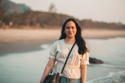 Portrait of young woman standing against lake