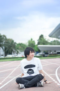 Young man sitting against sky