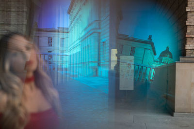 Blurred motion of woman on street against buildings in city