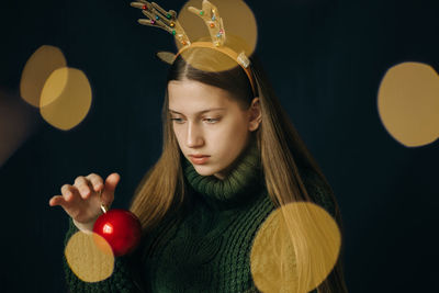 Teenager girl with christmas deer horns in a green sweater, sad.