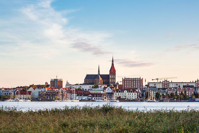 View of buildings at waterfront against cloudy sky