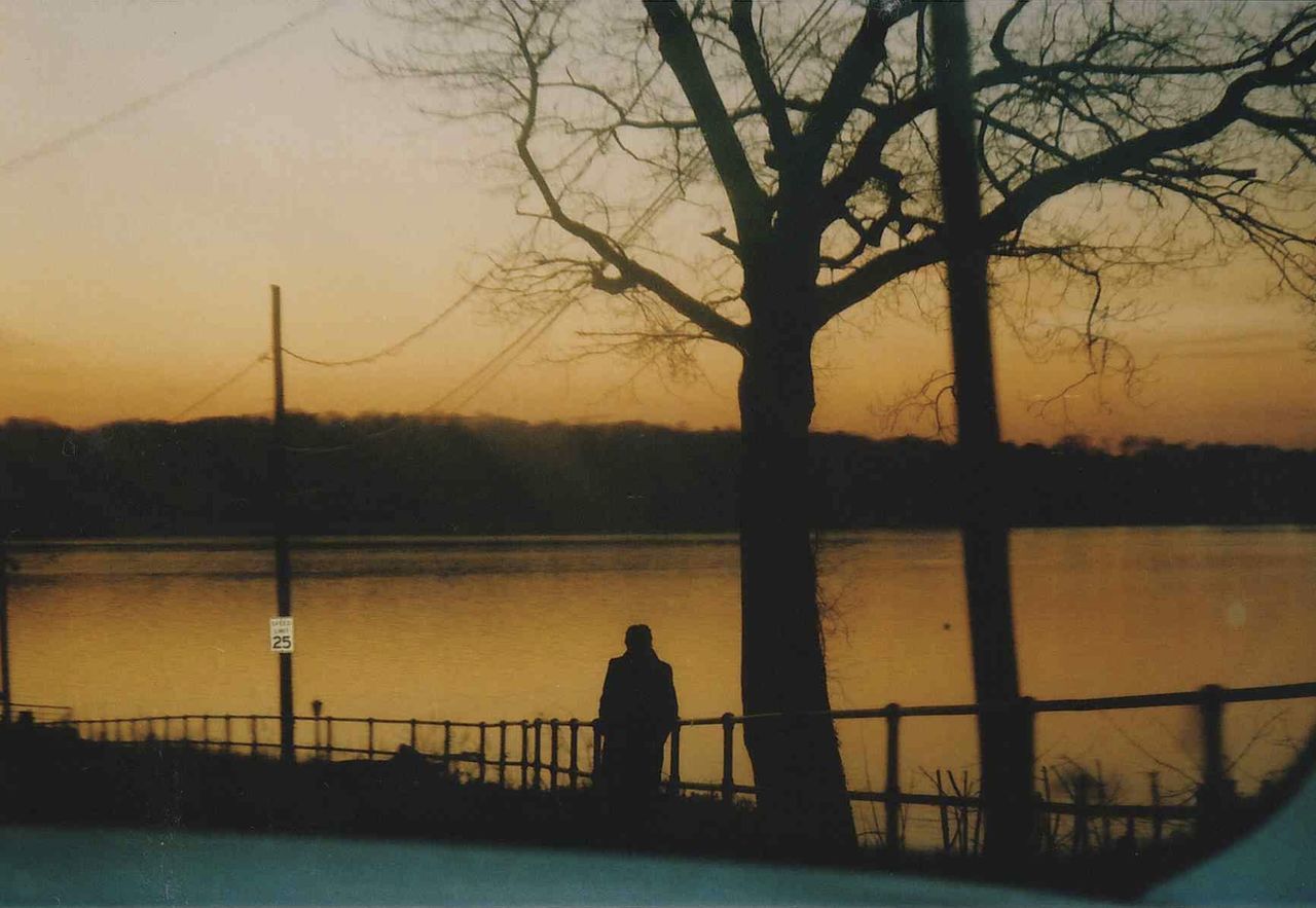 SILHOUETTE PEOPLE BY RIVER AGAINST SKY AT SUNSET