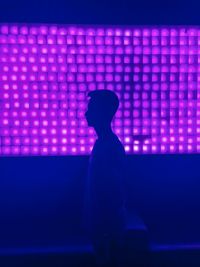 Silhouette of man standing against illuminated lights at night