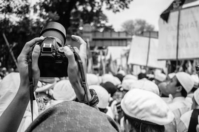 Midsection of woman photographing against sky