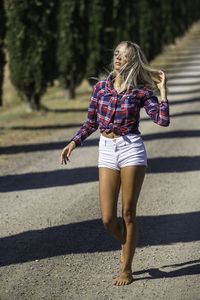 Full length of young woman walking on road