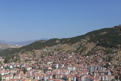 Aerial view of townscape by mountain against clear blue sky