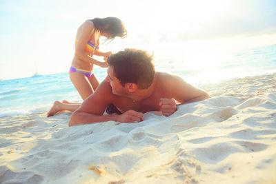 Father and son at beach against sky