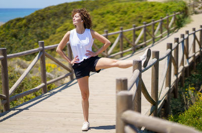 Portrait of young woman standing on railing