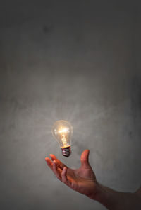 Close-up of hand holding illuminated light bulb