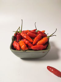 Close-up of red chili peppers on table against white background