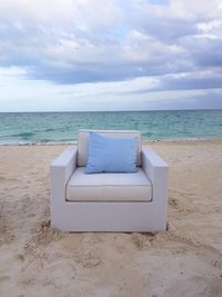 Chair on beach against sky