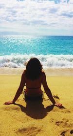 Rear view of woman relaxing at beach