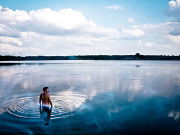 Man in swimming pool by lake against sky