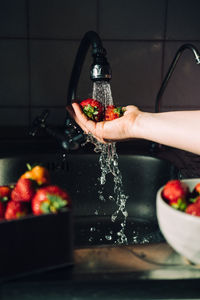 Woman hands washing fresh ripe strawberries in the kitchen. red vibrant strawberries under water 