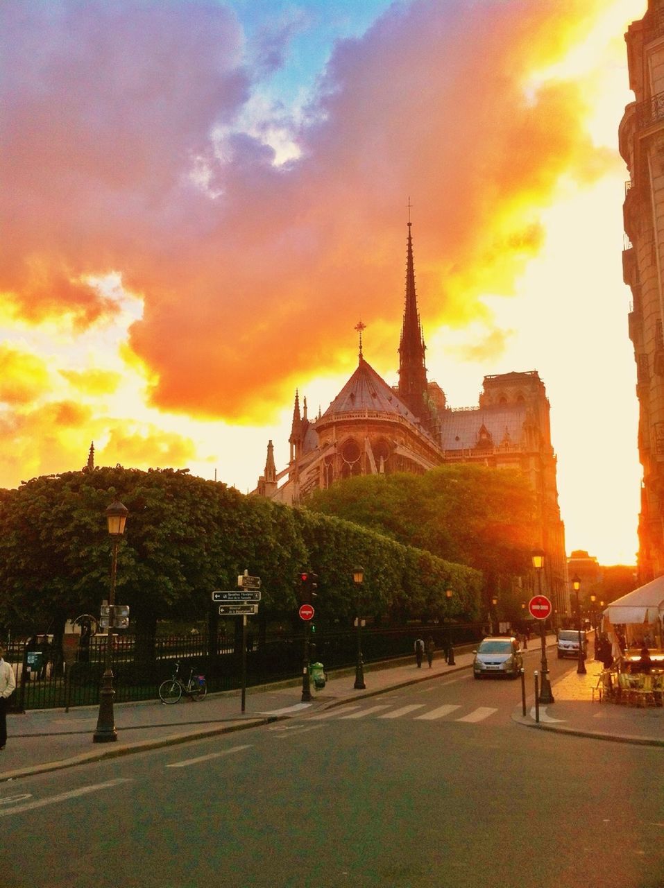 architecture, building exterior, built structure, sunset, sky, religion, place of worship, church, spirituality, famous place, car, transportation, travel destinations, travel, orange color, city, cloud - sky, street, land vehicle