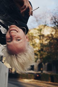 Mid adult woman upside down and holding a cigarette