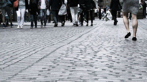 Low section of women walking on sidewalk in city