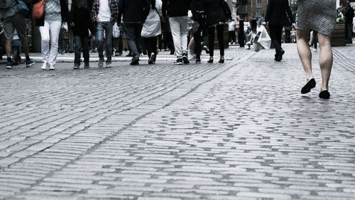 Low section of people walking on street in city